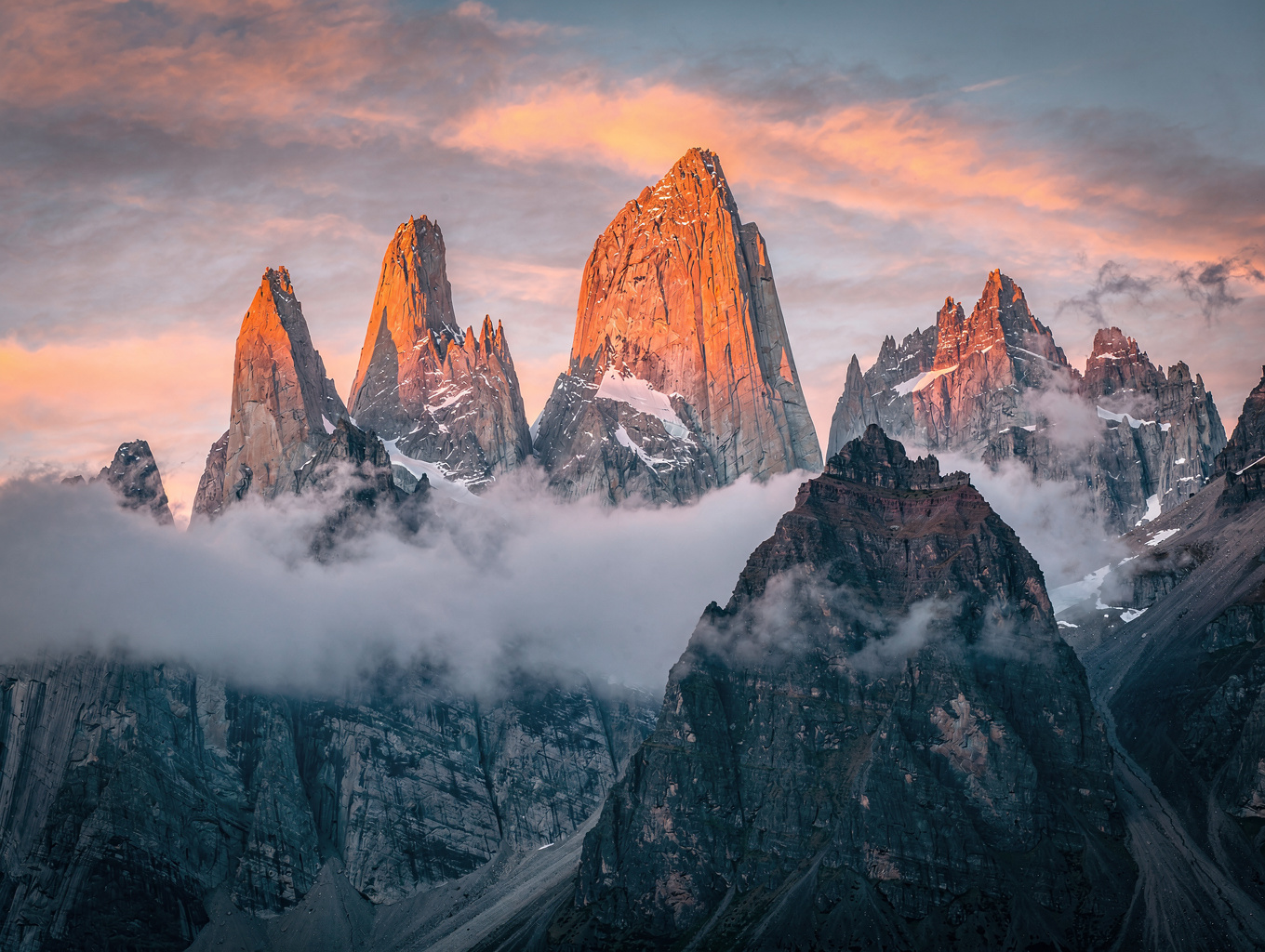 Granite needle of Cerro Torre lit with amber alpine glow beneath clearing storm clouds