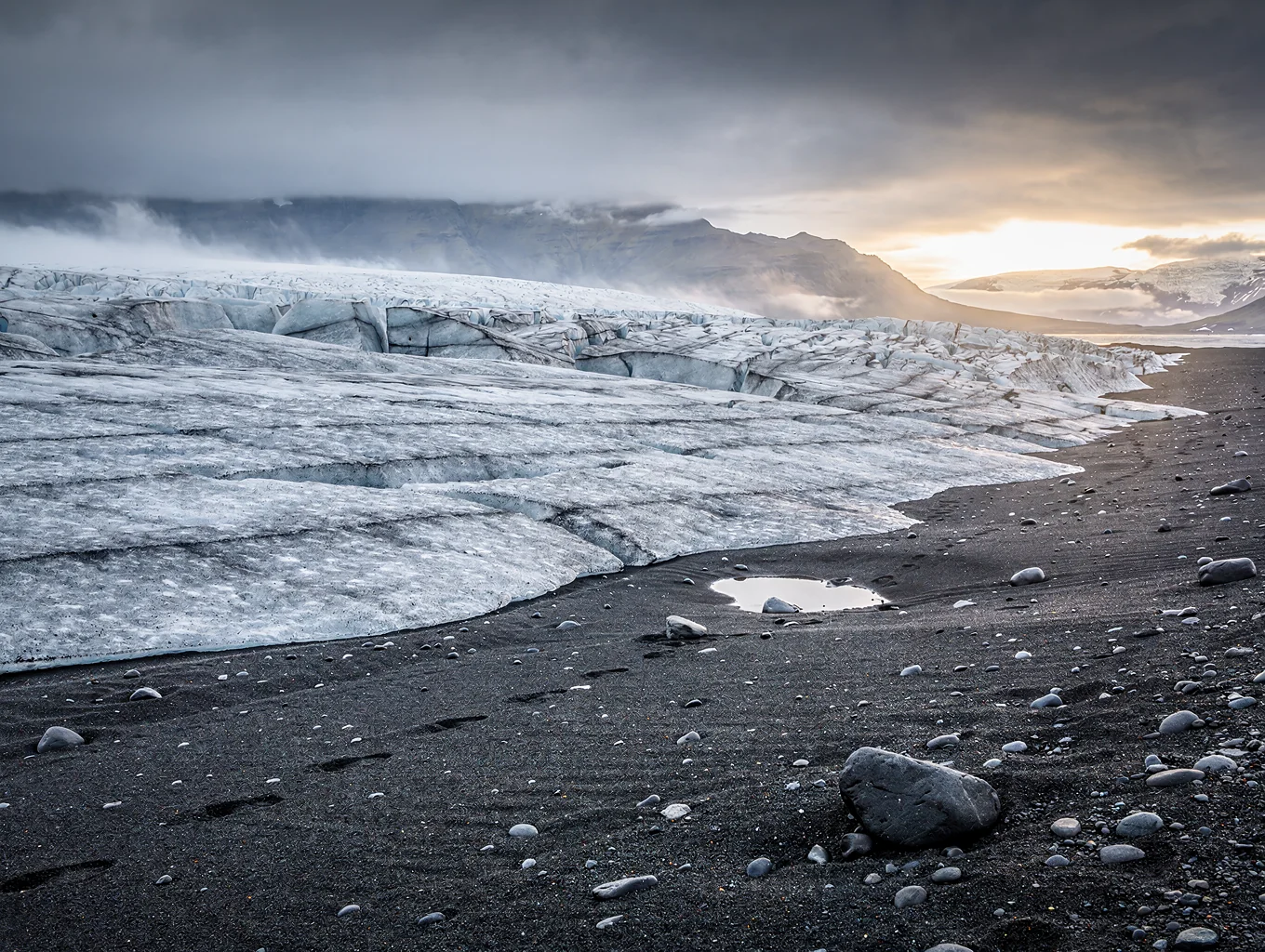 Sculpted blue iceberg chunk resting upon volcanic black basalt shoreline